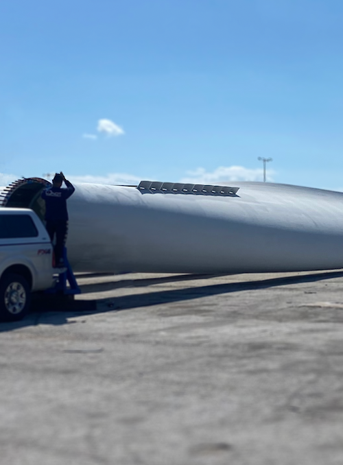 Wind turbine blades lying horizontally on the ground with a CICNDT work truck parked nearby, highlighting maintenance and inspection processes in the wind energy industry.