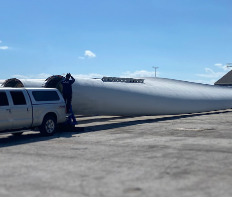 Wind turbine blades lying horizontally on the ground with a CICNDT work truck parked nearby, highlighting maintenance and inspection processes in the wind energy industry.